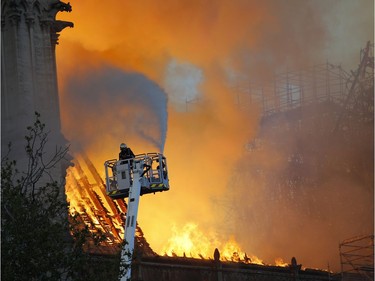 A fire fighter uses a hose as Notre Dame cathedral is burning in Paris, Monday, April 15, 2019. A catastrophic fire engulfed the upper reaches of Paris' soaring Notre Dame Cathedral as it was undergoing renovations Monday, threatening one of the greatest architectural treasures of the Western world as tourists and Parisians looked on aghast from the streets below.