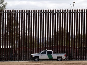 A U.S. Customs and Border Protection vehicle sits near the border wall.