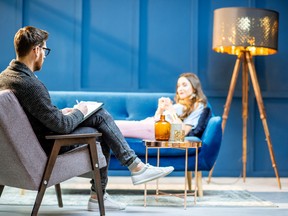 Young woman visiting male psychologist lying on the comfortable couch during psychological session in the luxury blue office interior