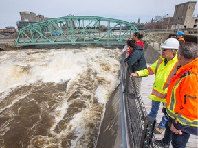 From the safety of the Zibi viewing platform visitors take photos of the enormous amounts of water flowing over the Chaudière Falls and under the closed Chaudière Bridge.  Wayne Cuddington / Postmedia