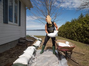Elisha Wallace helps build the sandbag barrier alongside her mom's home that looks out over the Ottawa River in the community of Constance Bay as area residents anticipate rising water from the Ottawa River could possibly cause major flooding.