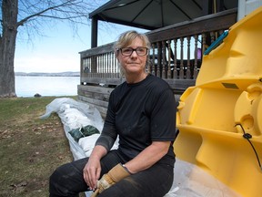 Janice Wallace sits on the sandbag barrier alongside her home that looks out over the Ottawa River in the community of Constance Bay as area residents anticipate rising water from the Ottawa River could possibly cause major flooding.