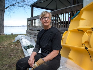 Janice Wallace sits on the sandbag barrier alongside her home that looks out over the Ottawa River in the community of Constance Bay as area residents anticipate rising water from the Ottawa River could possibly cause major flooding.