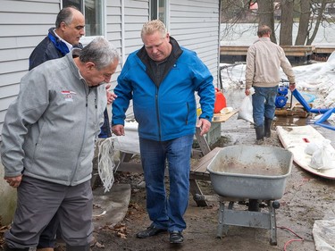 Premier Doug Ford visits the home of Jim (in background sandbagging) and Shannon Groves in Constance Bay on the Ottawa River as he came to assess the flood damage.
