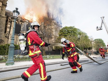 This photo provided Tuesday April 16, 2019 by the Paris Fire Brigade shows fire fighters pulling a hose by the burning Notre Dame cathedral, Monday April 15, 2019. Experts assessed the blackened shell of Paris' iconic Notre Dame Tuesday morning to establish next steps to save what remains after a devastating fire destroyed much of the cathedral that had survived almost 900 years of history. (Benoit Moser, BSPP via AP) ORG XMIT: PAR113