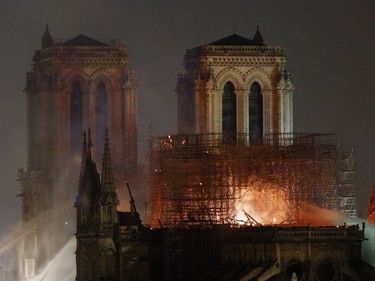 Firefighters tackle the blaze as flames and smoke rise from Notre Dame cathedral as it burns in Paris, Monday, April 15, 2019. Massive plumes of yellow brown smoke is filling the air above Notre Dame Cathedral and ash is falling on tourists and others around the island that marks the center of Paris.
