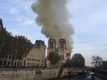 Notre Dame cathedral is burning in Paris, Monday, April 15, 2019. Massive plumes of yellow brown smoke is filling the air above Notre Dame Cathedral and ash is falling on tourists and others around the island that marks the center of Paris.