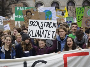 In this March 29 photo, Swedish climate activist Greta Thunberg, centre, lifts her sign which reads 'school strike for the climate' as she attends the 'Friday For Future' rally in Berlin, Germany.