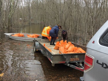 From left, Tom Crain, Tammy Crain and Brandon Crain, transfer sandbags from a trailer to an aluminum boat on the north shore of Dalhousie Lake on Saturday, April 27, 2019.