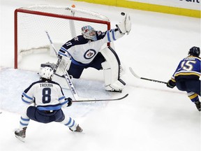 Winnipeg Jets goaltender Connor Hellebuyck gloves the puck as teammate Jacob Trouba (8) and St. Louis Blues' Robby Fabbri (15) watch during the first period in Game 6 of an NHL first-round hockey playoff series, Saturday, April 20, 2019, in St. Louis.