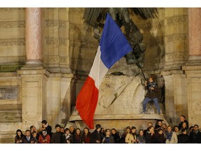 People attend a vigil in Paris, Tuesday April 16, 2019. Firefighters declared success Tuesday in a more than 12-hour battle to extinguish an inferno engulfing Paris' iconic Notre Dame cathedral that claimed its spire and roof, but spared its bell towers and the purported Crown of Christ.