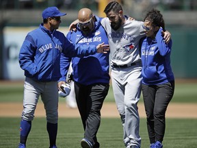 Toronto Blue Jays manager Charlie Montoyo, left, speaks with pitcher Matt Shoemaker, second from right, as Shoemaker is helped off the field after sustaining an injury during a rundown play against the Oakland Athletics in the third inning of a baseball game Saturday, April 20, 2019, in Oakland, Calif.
