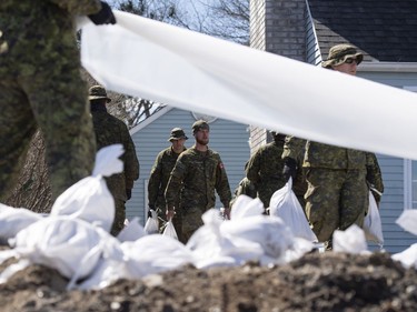 Canadian Forces members carry sandbags to build a wall to protect a home from the flooding Ottawa River in the Ottawa community of Constance Bay, on Tuesday, April 30, 2019.