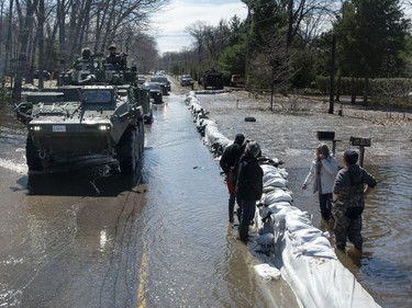 A Canadian Forces Light Armoured Vehicle passes peope standing in floodwaters on Bayview Drive in the Ottawa community of Constance Bay, during a guided tour of Canadian Armed Forces flood relief operations in the National Capital Region on Tuesday, April 30, 2019.