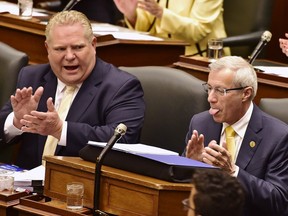 Ontario Finance Minister Vic Fedeli and Premier Doug Ford applaud as a page delivers copies of the 2019 budget at the legislature in Toronto on Thursday, April 11, 2019.