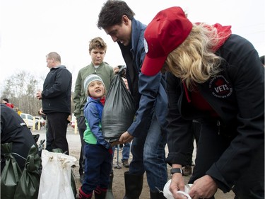 Prime Minister Justin Trudeau's son Hadrien tries to lift a sandbag as they help with flood relief efforts in the Ottawa community of Constance Bay on Saturday, April 27, 2019.
