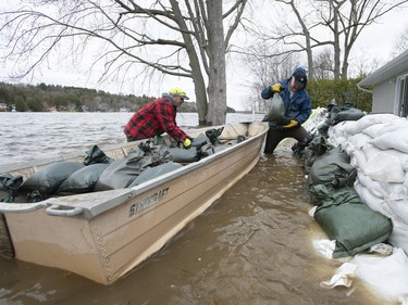 Dave Delle Palme, left, and Jeff Jessen build a wall of sandbags as the waters of the Ottawa River rise to the level of their friend's home in the Ottawa community of Constance Bay on Saturday, April 27, 2019.