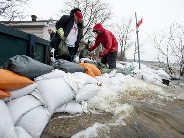 Waves from the Ottawa River crash against a wall of sandbags as Jim Schiavo, left, and Rob Hamilton try to reinforce it, at their friend's home in the Ottawa community of Constance Bay on Saturday, April 27, 2019.