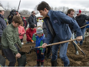 Prime Minister Justin Trudeau shovels sand to fill sandbags with his son Xavier, as son Hadrien watches, in the Ottawa community of Constance Bay as flooding continues to affect the region on Saturday, April 27, 2019.