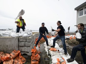 Workers prepare for higher flood waters on the Ottawa River in Britannia Bay, Ont. on Monday, April 29, 2019.
