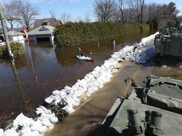 Media traveling with the Canadian Armed Forces during a flooding tour of Constance Bay in Ottawa Tuesday April 30, 2019. Members got a opportunity to watch the Canadian Armed Forces flood relief operations Tuesday. A woman carries sandbags in a canoe to her home.