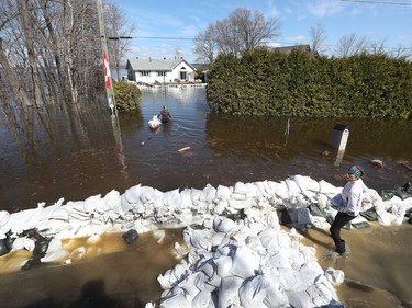 Media traveling with the Canadian Armed Forces during a flooding tour of Constance Bay in Ottawa Tuesday April 30, 2019. Members got a opportunity to watch the Canadian Armed Forces flood relief operations Tuesday. A woman carries sandbags in a canoe to her home.