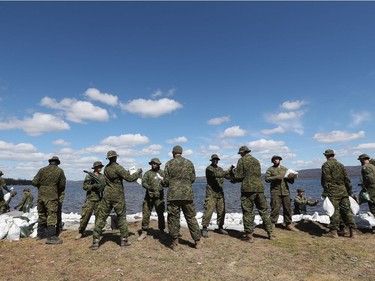 Soldiers pass sandbags in front of a home on Lane Street in Constance Bay.