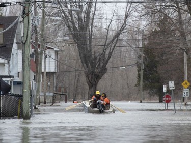 Utility workers use a boat to make their way along Rue Rene in Gatineau, Que. as flooding from the Ottawa River continues to affect the region on Saturday, April 27, 2019.