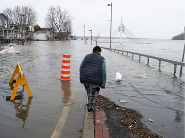 A boy walks along the curb as water from the Ottawa River floods onto Rue Jacques-Cartier in Gatineau, Que. on Saturday, April 27, 2019.