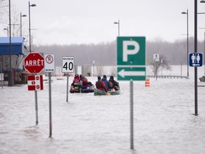 Police use an amphibious ATV while others paddle a canoe to access a stretch of Rue Jacques-Cartier covered by the high waters of the Ottawa River in Gatineau, Que. on Saturday, April 27, 2019.