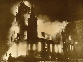 Fire rages through the Sacre Coeur Roman Catholic Church Friday as a fireman (foreground) looks on.