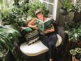 A woman reads amongst plants.