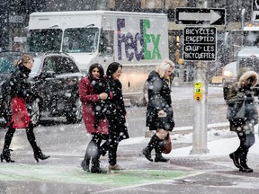Pedestrians at the corner of O'Connor and Laurier Streets are met with a snow squall as they head out for the lunch hour.