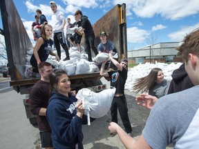 Students and faculty from West Carleton High School pitch in and fill a mountain of sandbags at the campus, to be picked up by residents and the city. Wayne Cuddington / Postmedia