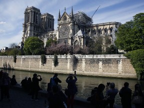 People watch Notre Dame cathedral, in Paris, Wednesday, April 17, 2019. Notre Dame Cathedral would have been completely burned to the ground in a "chain reaction collapse" had firefighters not moved rapidly in deploying their equipment to battle the blaze racing through the landmark monument, a Paris official said Wednesday.