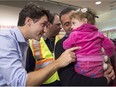 Prime Minister Justin Trudeau greets 16-month-old Madeleine Jamkossian, right, and her father Kevork Jamkossian, refugees fleeing the Syrian civil war, during their arrival at Pearson International airport, in Toronto on Dec. 11, 2015.