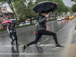 A man jumps over a large puddle at a pedestrian crossing.