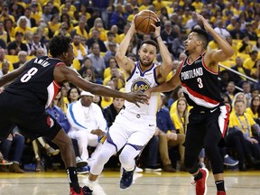 OAKLAND, CALIFORNIA - MAY 14: Stephen Curry #30 of the Golden State Warriors drives to the basket against Al-Farouq Aminu #8 and CJ McCollum #3 of the Portland Trail Blazers during the first half in game one of the NBA Western Conference Finals at ORACLE Arena on May 14, 2019 in Oakland, California.