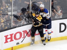 Matt Grzelcyk of the Bruins and Alex Pietrangelo of the Blues battle along the boards during the first period in Game 1 of the Stanley Cup final at Boston on Monday night.