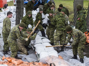 Members of the Canadian Armed Forces build a wall of sandbags to protect property against flood water in the Britannia area of Ottawa on May 1, 2019.