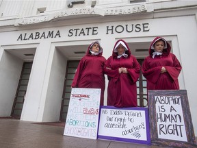 FILE - In this April 17, 2019, file photo, Bianca Cameron-Schwiesow, from left, Kari Crowe and Margeaux Hartline, dressed as handmaids, protest against a bill banning nearly all abortions at the Alabama State House in Montgomery, Ala. As abortion opponents cheer the passage of fetal heartbeat laws and other restrictions on the procedure, abortion-rights groups have been waging a quieter battle in courthouses around the country to overturn limits on providers.