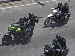 National Bolivarian Police officers open fire against opposition demonstrators during clashes after troops joined opposition leader Juan Guaido in his campaign to oust Maduro's government, in the surroundings of La Carlota military base in Caracas on April 30, 2019.