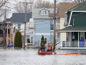 Two men paddle along Jacques-Cartier street past sandbagged and flooded homes in Gatineau on Thursday May 2, 2019.