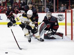 Boston Bruins' Jake DeBrusk chases the puck while Carolina Hurricanes' Brett Pesce and goalie Curtis McElhinney defend the net during the first period in Game 3 of the NHL hockey Stanley Cup Eastern Conference final series in Raleigh, N.C., Tuesday.