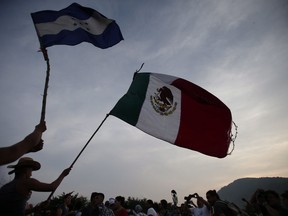 Migrants wave the flags of Honduras and Mexico as they stand stalled after Mexican police blockaded the road to keep them from advancing, outside the town of Arriaga, Chiapas State, Mexico on October 27, 2018. The United Nations is urging Canada to help ease Mexico's refugee burden by helping resettle some of the most vulnerable of its new arrivals, including women, children and LGBTQ people. Mexico is feeling the squeeze from an unprecedented exodus of people fleeing Central American countries and some of the worst violence from nations not at actually war is forcing families northward. "Our pitch to Canada is to do more," said Mark Manly, the Mexico representative of the United Nations High Commissioner for Refugees.