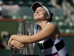 FILE - In this Sunday, March 17, 2019 file photo, Bianca Andreescu, of Canada, smiles as she hugs her trophy after defeating Angelique Kerber, of Germany, in the women's final at the BNP Paribas Open tennis tournament, in Indian Wells, Calif. It's typically Canadian that Denis Shapovalov, Felix Auger-Aliassime and Bianca Andreescu are each children of immigrants. What's not typical is that they have all simultaneously broken into the world's elite ranks of tennis players _ and will all be worth watching when the French Open begins Sunday.