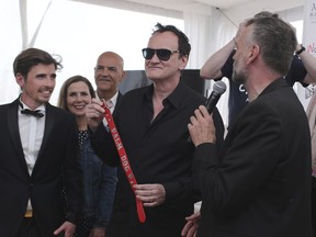 Director Quentin Tarantino poses for photographers with the Palm Dog collar award for the the dog Brandy that appeared in his film 'Once Upon a Time in Hollywood' at the 72nd international film festival, Cannes, southern France, Friday, May 24, 2019.