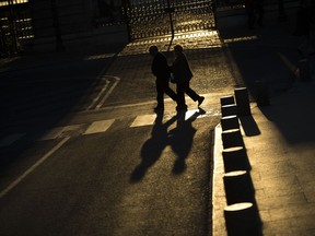 FILE - In this Tuesday, April 4, 2017 file photo, an elderly couple walks across a street near the Royal Palace in Madrid. If you want to save your brain, focus on keeping the rest of your body well with exercise and healthy habits rather than popping vitamin pills, say new World Health Organization guidelines for preventing dementia, released on Tuesday, May 14, 2019.