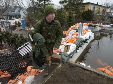 Members of the Canadian Forces climb a sandbag wall as they make their way to help with flood defences along the Ottawa River, Wednesday, May 1, 2019 in Ottawa.