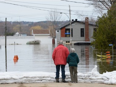 A couple surveys floodwaters from behind a row of sandbags on the street in an east end community of Ottawa, Wednesday, May 1, 2019.